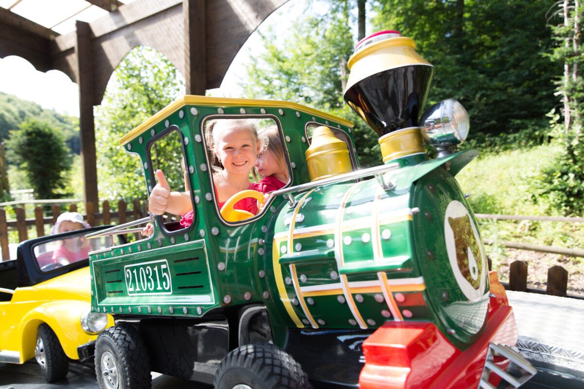 Kinderen in een miniatuurtrein sturen vrolijk over een vast parcours in een kindvriendelijk pretpark.
