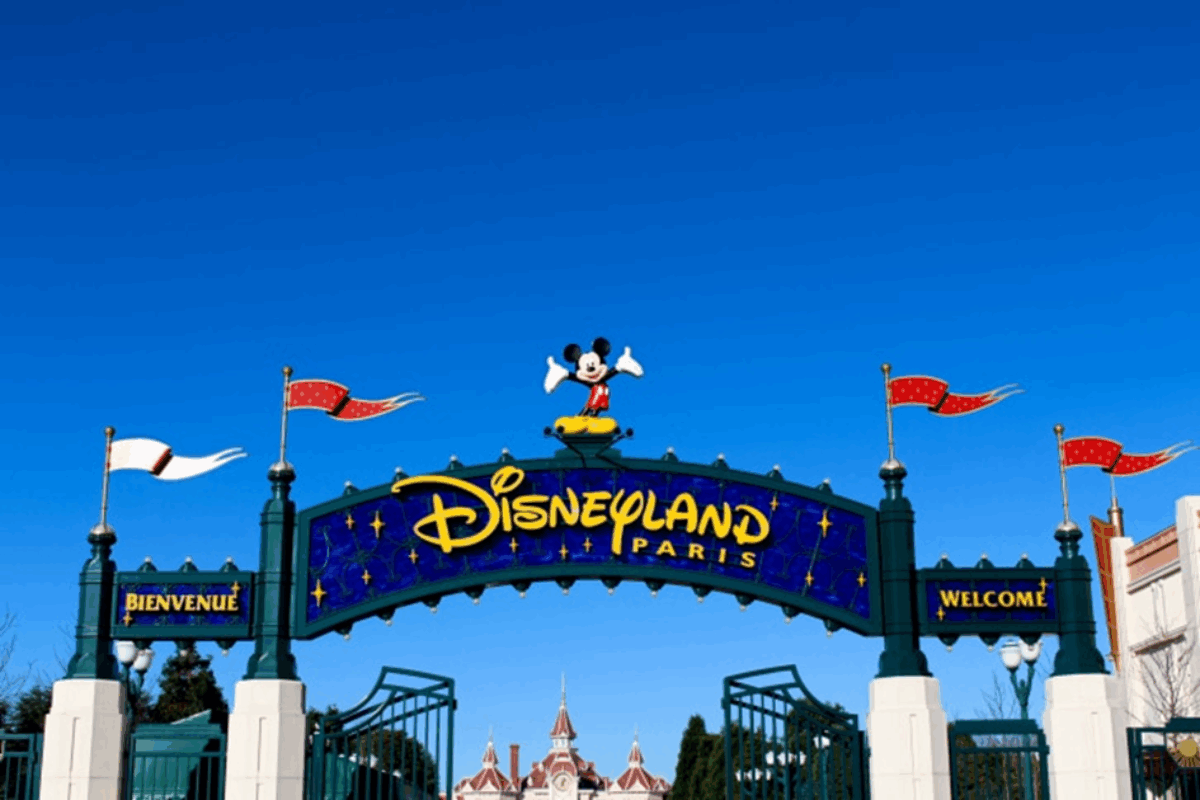 Ingang van Disneyland Paris met het roze kasteel en bezoekers op het plein.