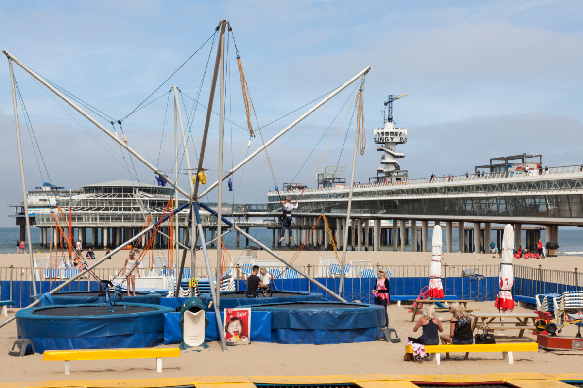 Kinderen spelen op trampolines en bungee-attractie bij het strand en de pier van Scheveningen