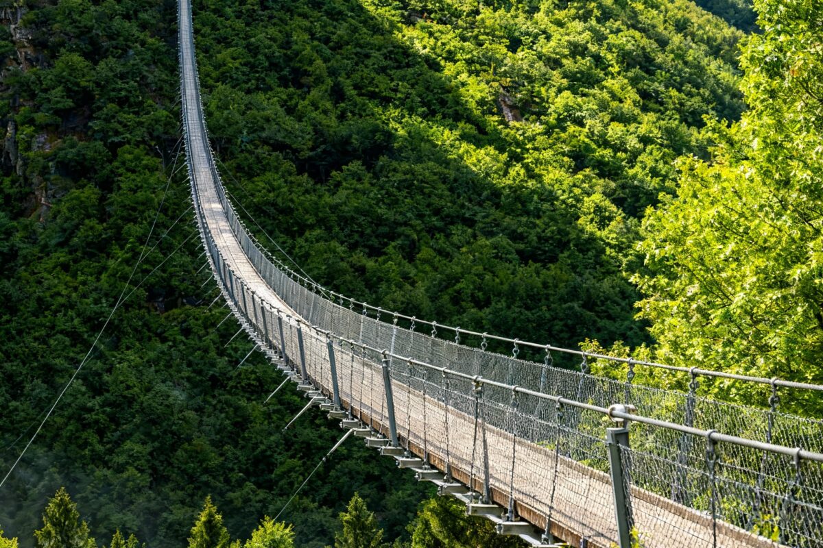 De Geierlay-hangbrug in de Eifel, Duitsland – een 360 meter lange voetgangersbrug die hoog boven een groen bebost dal hangt.