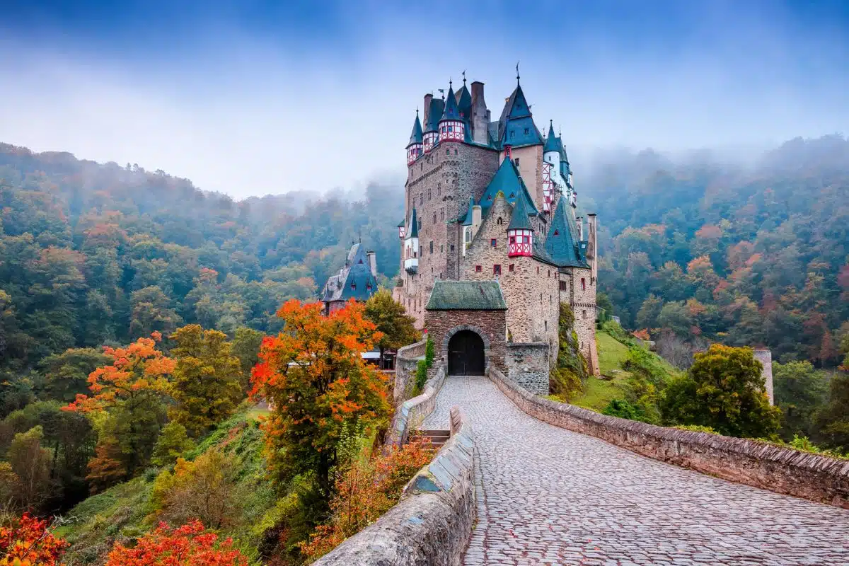 Uitzicht op Burg Eltz, een middeleeuws kasteel midden in het bosrijke heuvellandschap van de Eifel in Duitsland, bij zonsondergang.