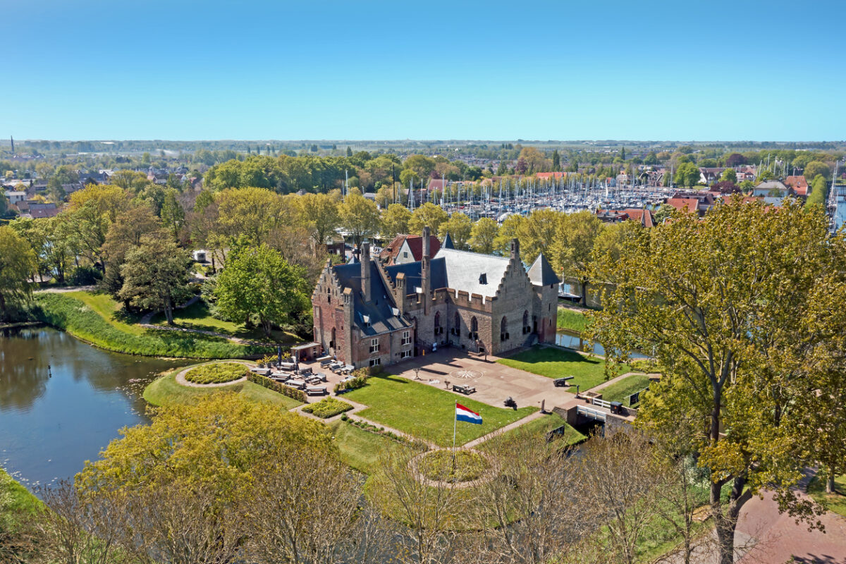 Kasteel Radboud in Medemblik gezien vanuit de lucht, omringd door water en groene bomen.