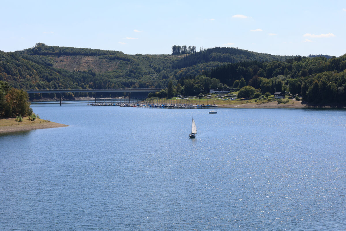 Zeilboot op de Biggesee in het Sauerland met brug en jachthaven bij Sondern op de achtergrond.
